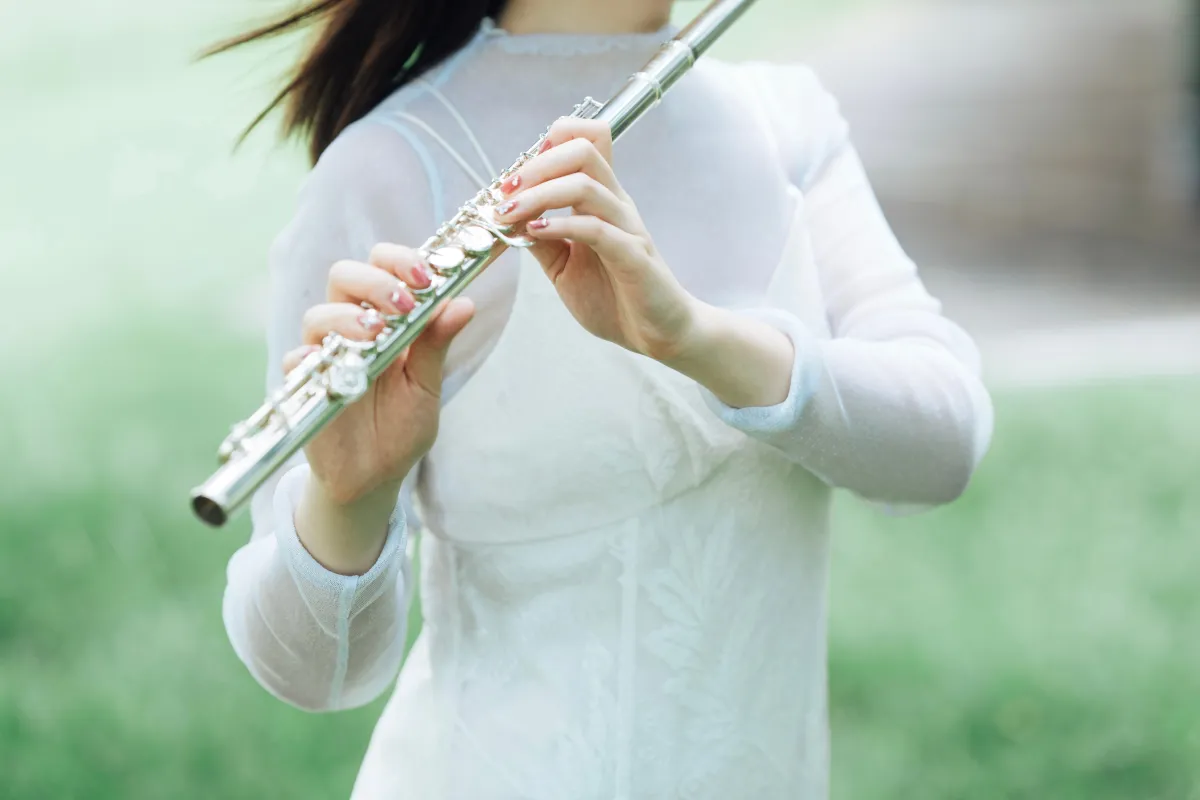 立ってフルートを吹く永田梨紗の手元のアップの写真